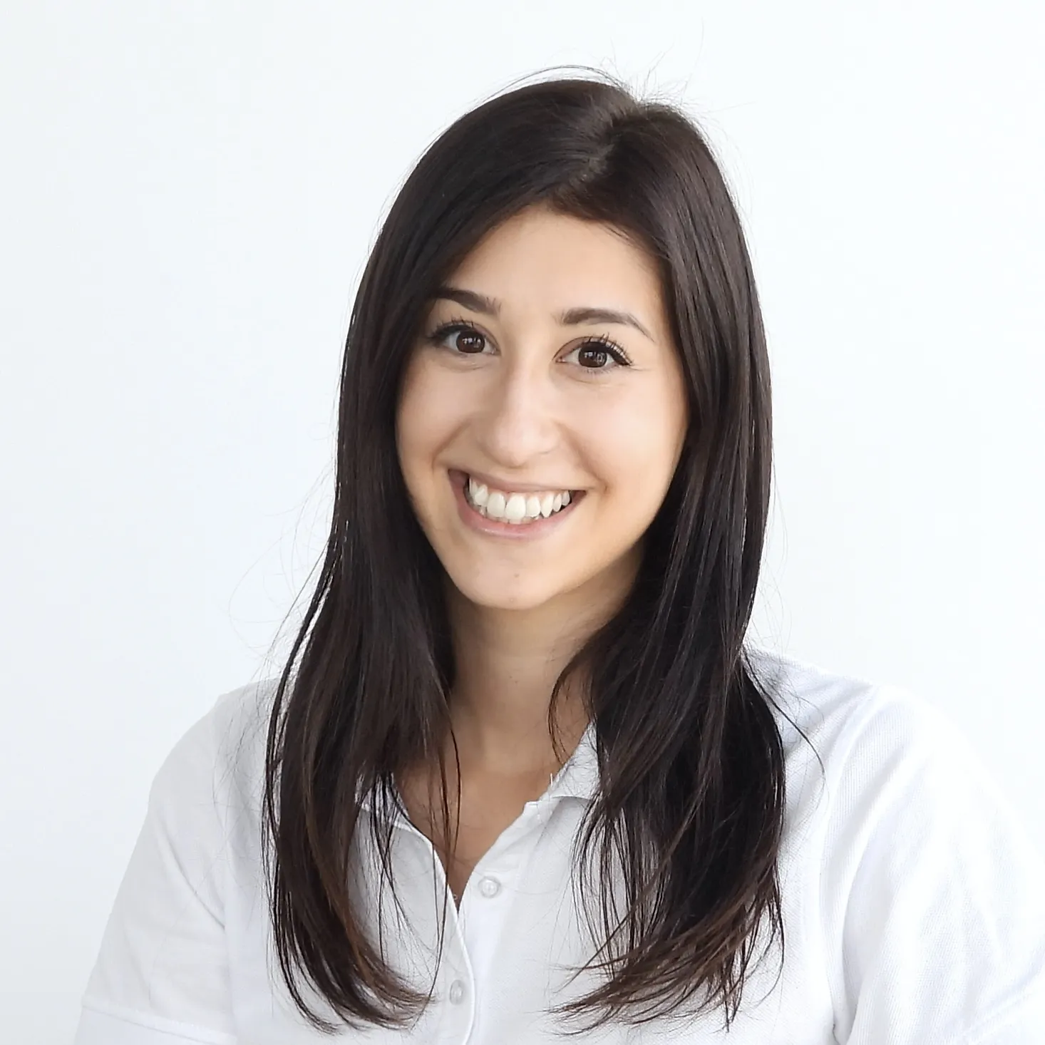 Sie trägt ein weisses Oberteil und hat dunkle, glatte Haare – sie lächelt offen.