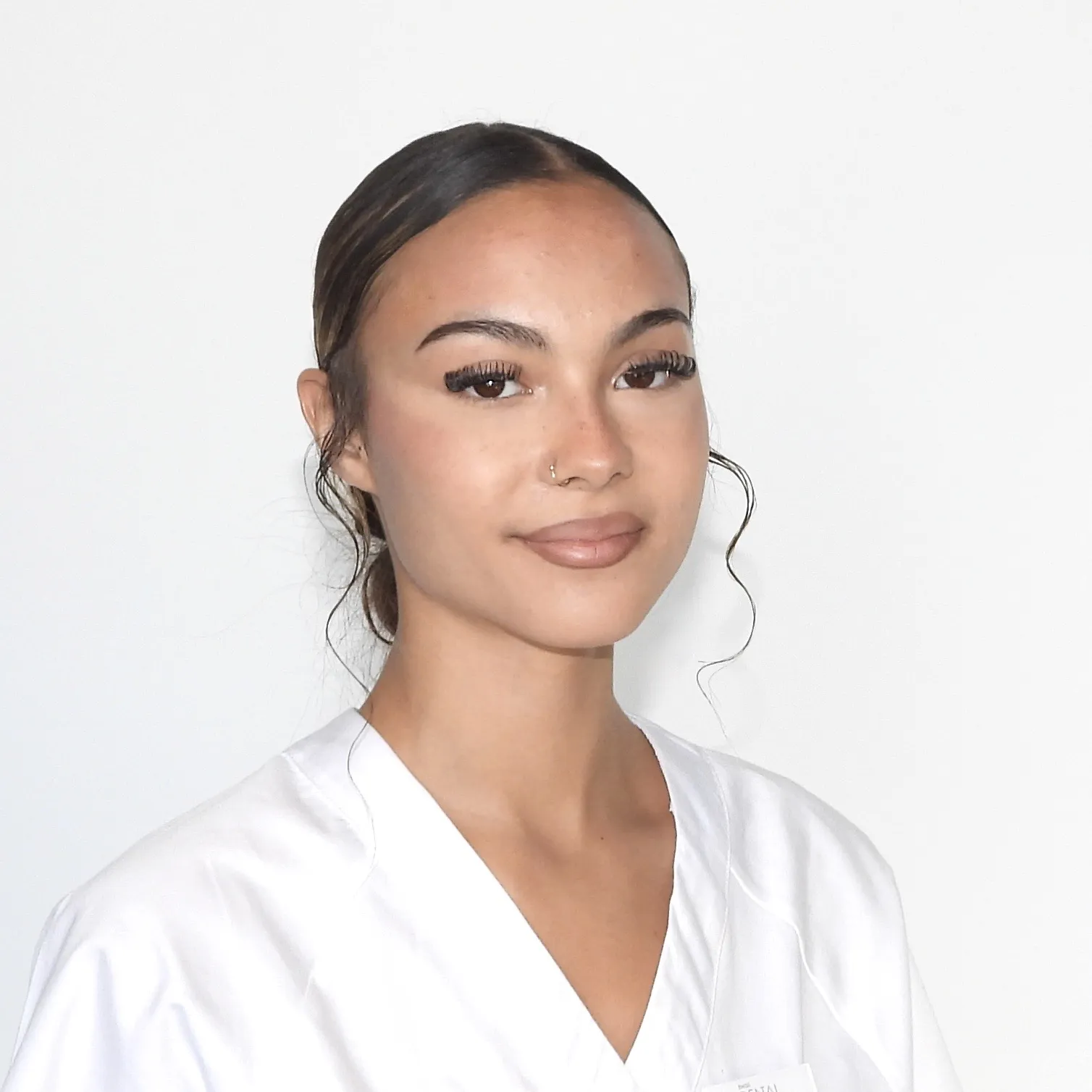 Sie hat das Haar zu einem Dutt gebunden, trägt ein weisses Oberteil und wirkt konzentriert.