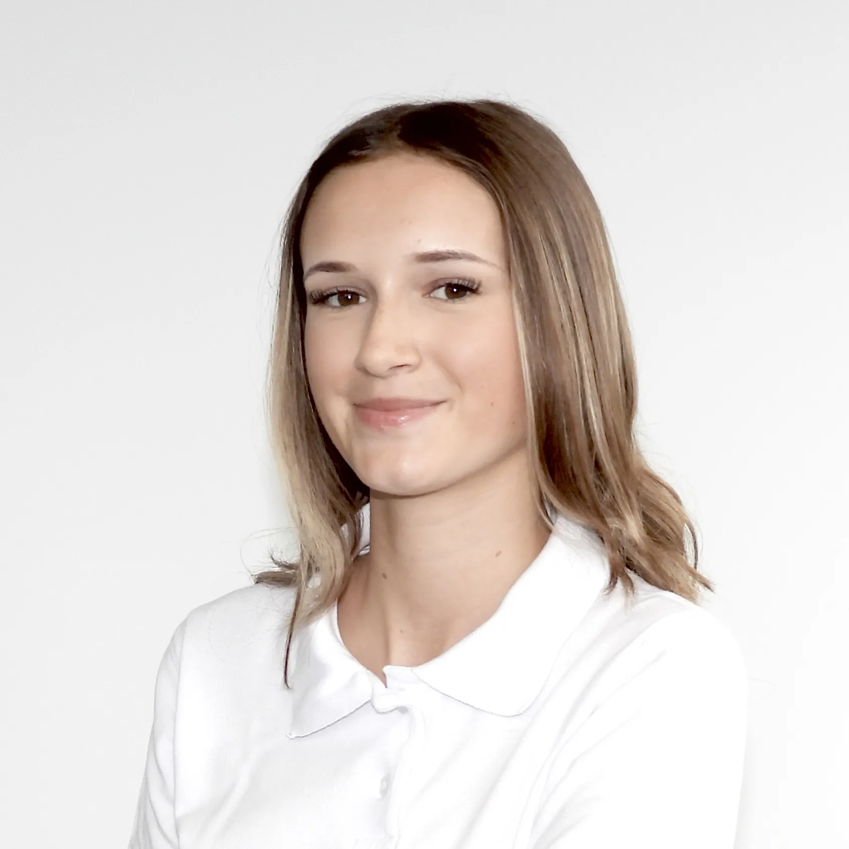 Sie trägt ihr glattes Haar offen, schaut freundlich in die Kamera und trägt Weiss.