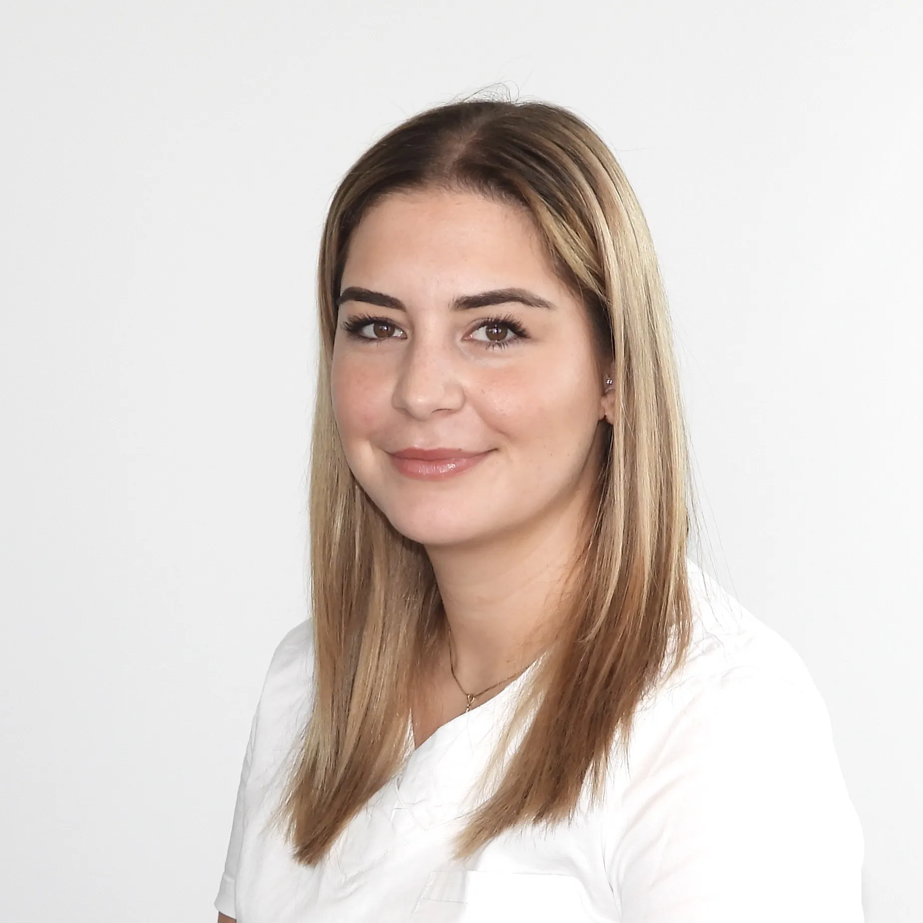 Sie lächelt leicht und trägt ihr glattes Haar offen.