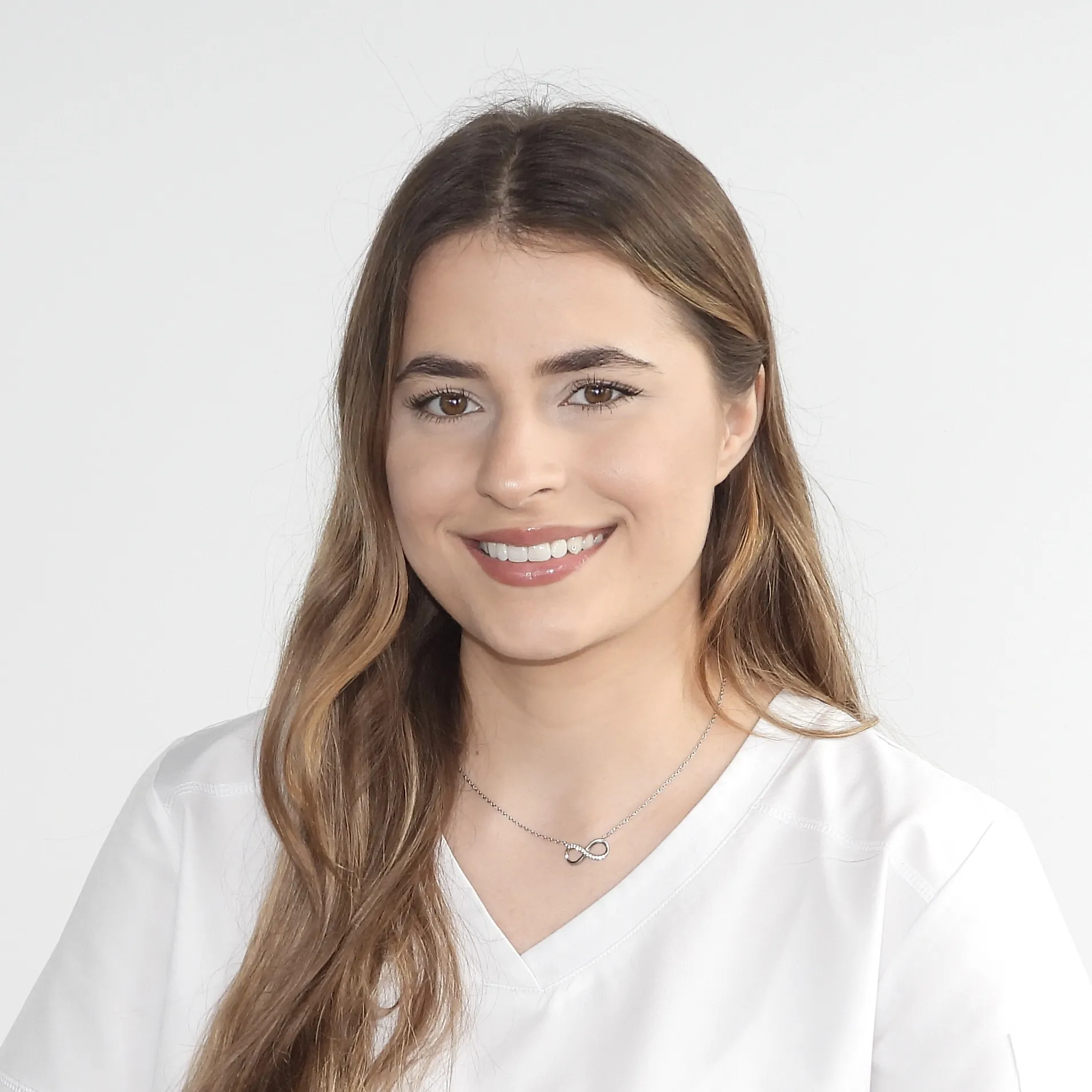 Sie trägt ein weisses Oberteil und hat langes, glattes Haar.